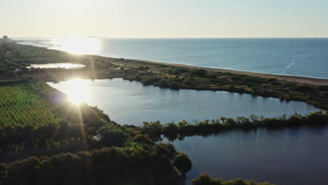 Beautiful-sunset-over-vineyards-pond-beachfront-the-mediterranean-sea-aerial