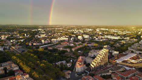Golden-hour-cityscape-of-Montpellier,-punctuated-by-the-arc-of-a-radiant-rainbow