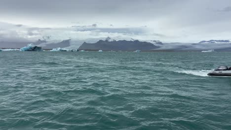 Person-on-zodiac-sailing-the-cold-waters-of-Jokulsarlon-lake-among-icebergs-in-Iceland