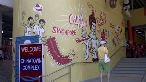 Hombre-Caminando-Junto-Al-Mural-De-Bruce-Lee-En-La-Entrada-Lateral-Del-Complejo-Chinatown-En-Singapur