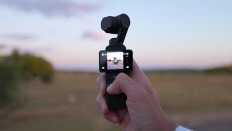 DJI-Osmo-Pocket-3-Held-In-Hand-With-Gimbal-Head-Being-Moved-By-Finger-Pressing-On-Button