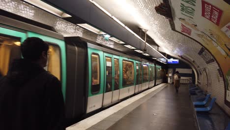 Der-U-Bahn-Zug-Verlässt-Den-Bahnhof-Paris-Frankreich-Stalingard,-Während-Menschen-Zu-Fuß-Vorbeikommen