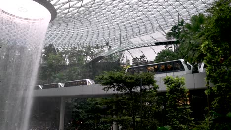The-Rain-Vortex-Indoor-Waterfall-At-Jewel-Changi-Airport-Singapore-With-Skytrain's-Going-Past