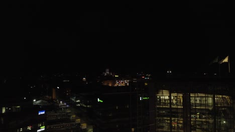 Black-night-aerial-rises-over-illuminated-buildings,-downtown-Helsinki