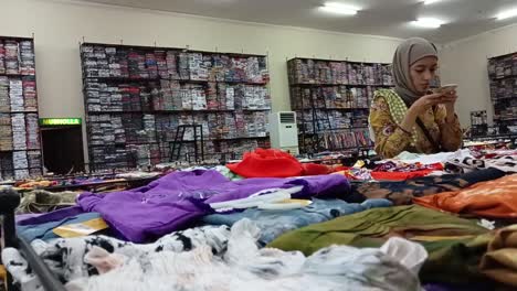 A-woman-is-choosing-a-mini-negligee-at-the-Krisna-shop,-the-largest-souvenir-and-clothing-center-in-Bali,-Indonesia