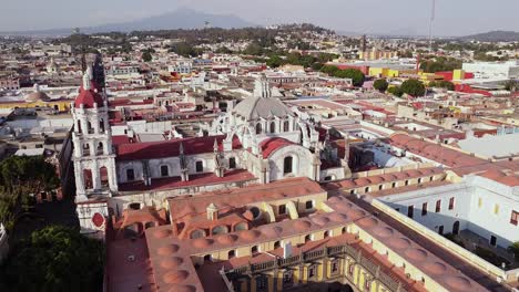 Aerial-bird's-eye-view-panoramic-forward-shot-over-a-historical-church-in-Puebla,-Mexico-at-daytime-with-the-historical-center-mexican-interesting-spots-for-travel-in-america