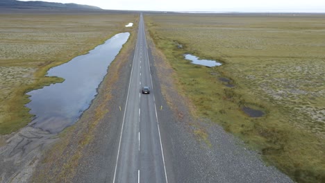 A-grey-2021-Mazda-3-advances-along-an-Icelandic-road,-the-journey-highlighted-by-open-grassy-plains-and-a-cloudy-sky,-encapsulated-in-smooth-4K