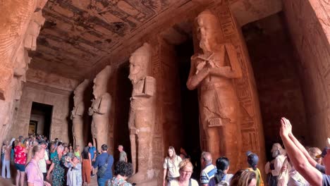 Large-group-of-tourists-raise-hands-with-phones-and-cameras-to-take-pictures-of-epic-statues-at-entrance-to-grand-site