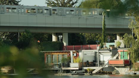 Subway-driving-past-waterfront-property-in-Vienna-Alte-Donau-over-bridge