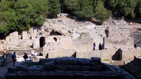Curious-Tourists-Explore-the-Ancient-Treasure-of-Butrint's-Amphitheater,-a-Mesmerizing-Archaeological-Site