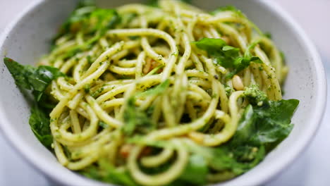 Spaghetti-and-pesto-with-rocket-and-pinenuts-rotating-in-a-bowl