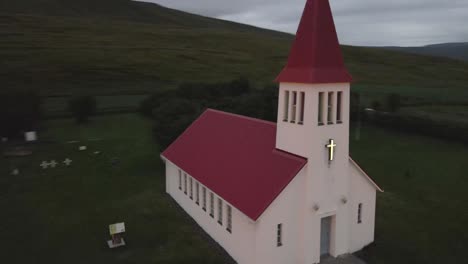 In-4K,-a-solitary-white-church-with-a-red-roof-called-Laufáskirkja-stands-in-stark-beauty-against-Iceland's-sparse-grasslands,-a-colonial-beacon-in-a-quaint-town-setting