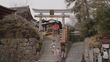 Young-Asian-girls-in-kimono-walking-up-staircase-to-deserted-Jishu-jinja-Shrine-inside-Kiyomizudera-Temple-in-Kyoto-during-the-pandemic