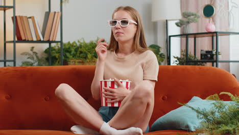 Woman-sitting-on-couch-eating-popcorn-and-watching-interesting-TV-3D-film,-sport-game-online-at-home