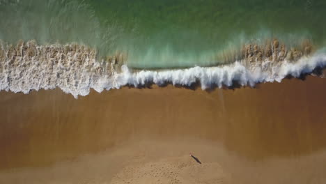 Cinematic-aerial-drone-looking-down-person-standing-still-on-beach-stunning-blue-water-golden-sand-coastline-morning-surf-huge-glassy-waves-crashing-swell-beautiful-Hossegor-Seignosse-France-Biarritz