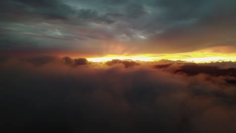 Artistic-Natural-Scenery,-Orange-Sun-Rays-Gleaming-Through-Dark-Clouds-At-Sunset,-4K-Drone