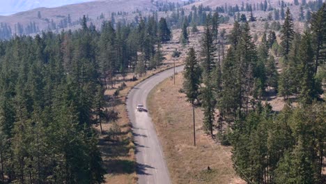 Aerial-View-of-Pickup-Truck-Journeying-Through-Deserted-Forested-Road