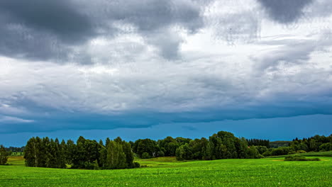 Grüne-Wiese-Mit-Bäumen-Und-Blauem-Bewölktem-Himmel-Im-Zeitraffer,-Filmische-Ländliche-Landschaft