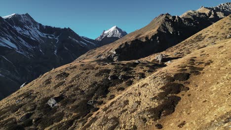 Flug-über-Bergige-Landschaft-In-Tibet,-Schneebedeckte-Landschaft-In-Der-Ferne,-Blaue-Himmelsantenne