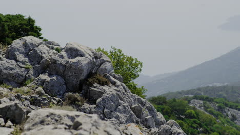 Satic-view-of-granite-cliff-with-green-shrubbery-overlooking-sweeping-valley-in-Croatia