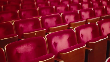 Slow-tracking-movement-over-worn-empty-red-velvet-theatre-audience-chairs