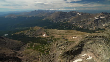 Cinematic-top-of-Rocky-Mountain-National-Park-Colorado-Denver-Boulder-Estes-Park-14er-Longs-Peak-looking-out-to-Indian-Peaks-cloudy-late-summer-dramatic-melting-snow-stunning-landscape-pan-left