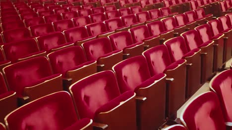 Wide-shot-passing-by-empty-red-audience-seats-in-an-empty-public-theatre