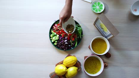 Assembling-salad-aerial-shot-of-salad-on-platform-black-beans-lemons-pumpkin-seeds-avocado-tomatoes-leaf-spinach-dressing