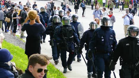 Eine-Interventionsgruppe-Der-Polizei-Läuft-Auf-Dem-Bürgersteig-Mit-Bürgern,-Die-Anti-G7-Proteste-Beobachten