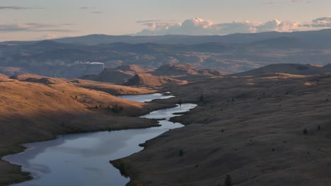 Die-Schönheit-Der-Natur-Wird-Enthüllt:-Luftaufnahme-Des-Sonnenuntergangs-über-Grasland,-See-Und-Majestätische-Hügel