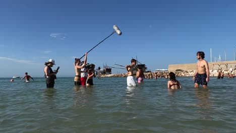 Film-troupe-bathing-in-water-filming-scenes-of-boys-and-girls-playing-in-sea-in-summer-season-for-film-production