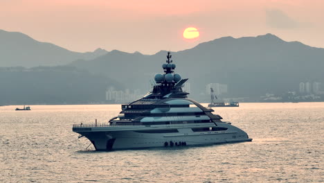 Luxury-Private-Super-Yacht-Anchored-in-Hong-Kong,-Sunset,-Cinematic-Aerial-Panning-Shot