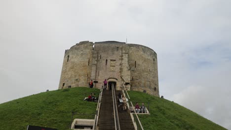 hand-held-shot-of-tourists-walking-up-to-the-entrance-at-Cliffords-Tower,-York