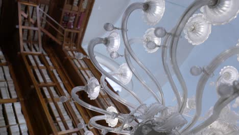Vertical---Glass-Chandelier-Against-Wooden-Bookshelves-In-Teresiana-Library-In-Mantua,-Italy