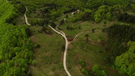 Aerial-drone-view-over-curved-road-leading-to-forest