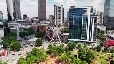 Aerial-view-of-turning-Ferris-Wheel-surrounded-by-modern-high-rise-downtown-buildings