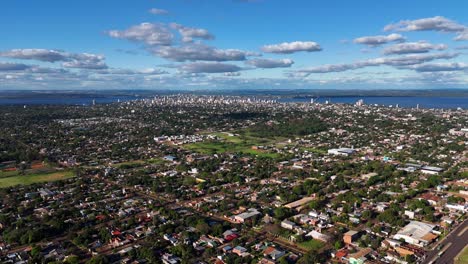 Aerial-hyperlapse-showcasing-the-charming-city-of-Posadas,-Misiones,-Argentina,-against-a-backdrop-of-beautiful-clouds-and-a-clear-blue-sky