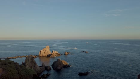 Vista-Lejana-De-Barcos-Cruzando-El-Mar-Al-Atardecer,-Vista-Desde-La-Playa-La-Calilla-En-España