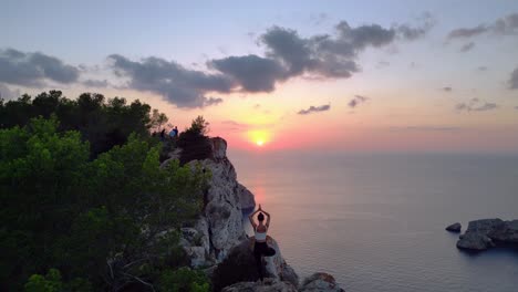 Wonderful-aerial-top-view-flight-Ibiza-cliff-Yoga-tree-pose-model-girl-sunset-evening