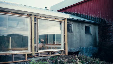 Mann-Installiert-Holzbretter-Auf-Glasfenster-Wandrahmen-Eines-Hauses