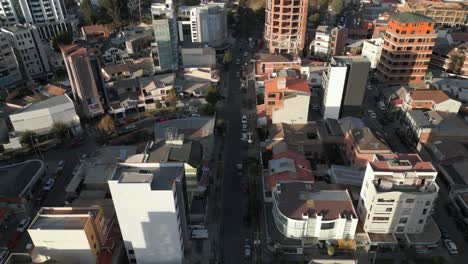 Aerial-drone-tilt-up-shot-over-roads-on-both-sides-of-city-buildings-in-La-Paz,-Bolivia-on-a-sunny-day
