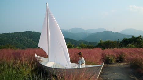 Child-Playing-Inside-Wooden-Sail-Boat-at-Pink-Muhly-Grass-Field---Herb-Island-Farm-in-Pocheon