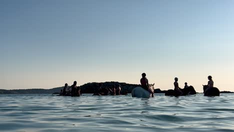 People-bathing-and-riding-horse-immersed-in-sea-water-in-summer-season-at-sunset