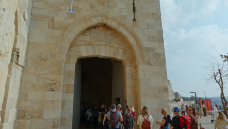 Handheld-shot-of-tourists-entering-Jaffa-gate-on-sunny-day,-Jerusalem,-Israel