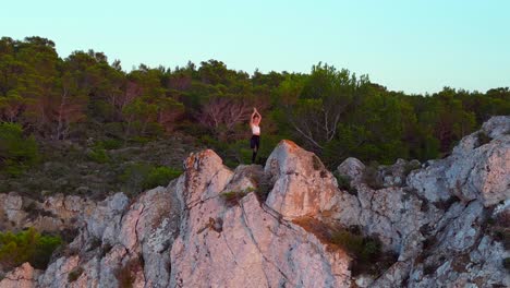 Beautiful-aerial-top-view-flight-Ibiza-cliff-Yoga-tree-pose-model-girl-sunset-evening