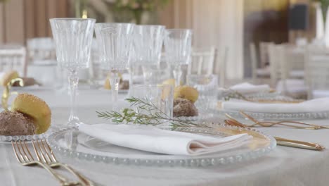 Slolw-4k-orbit-close-up-around-beautifully-decorated-wedding-dinner-table-with-classy-cutlery,-glasses,-bread-and-flower-arrangement