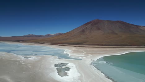 Aerial-drone-rotating-shot-over-partly-frozen-lake-at-the-foothills-of-a-mountain-range-in-Bolivia-at-daytime