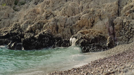 Turquoise-green-ocean-water-gently-crashes-onto-pebble-limestone-sand-of-blue-lagoon-beach-croatia