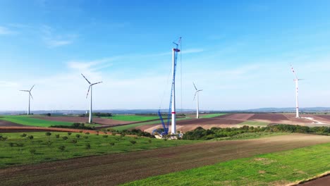 Scenic-Farm-With-Wind-Turbine-Under-Construction-During-Summer---aerial-drone-shot