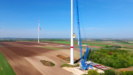 Construction-Of-A-Wind-Turbine-With-Large-Crane-In-Summer---drone-shot